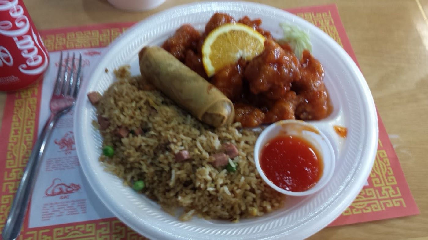Orange chicken with an egg roll, fried rice and sweet and sour sauce
